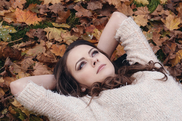 Relaxing woman among autumn leaves, embodying peace at the Wellness Make & Take Yoga Day Retreat at Purple Haven.