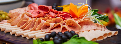 Charcuterie-style dinner spread with sliced meats, olives, and greens for Paint Night on the Farm with Dinner, June 14.